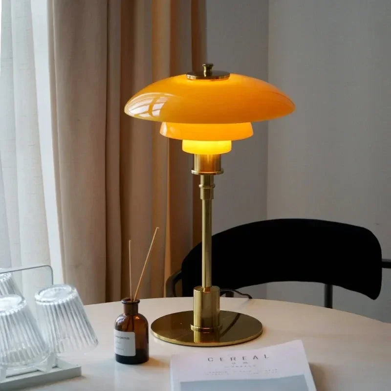 Nordic tiered glass table lamp in Antique Gold on a bedside table