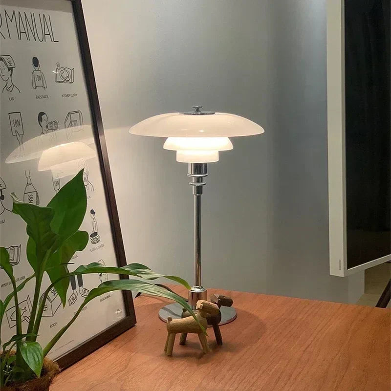 Tiered glass table lamp switched on with warm light