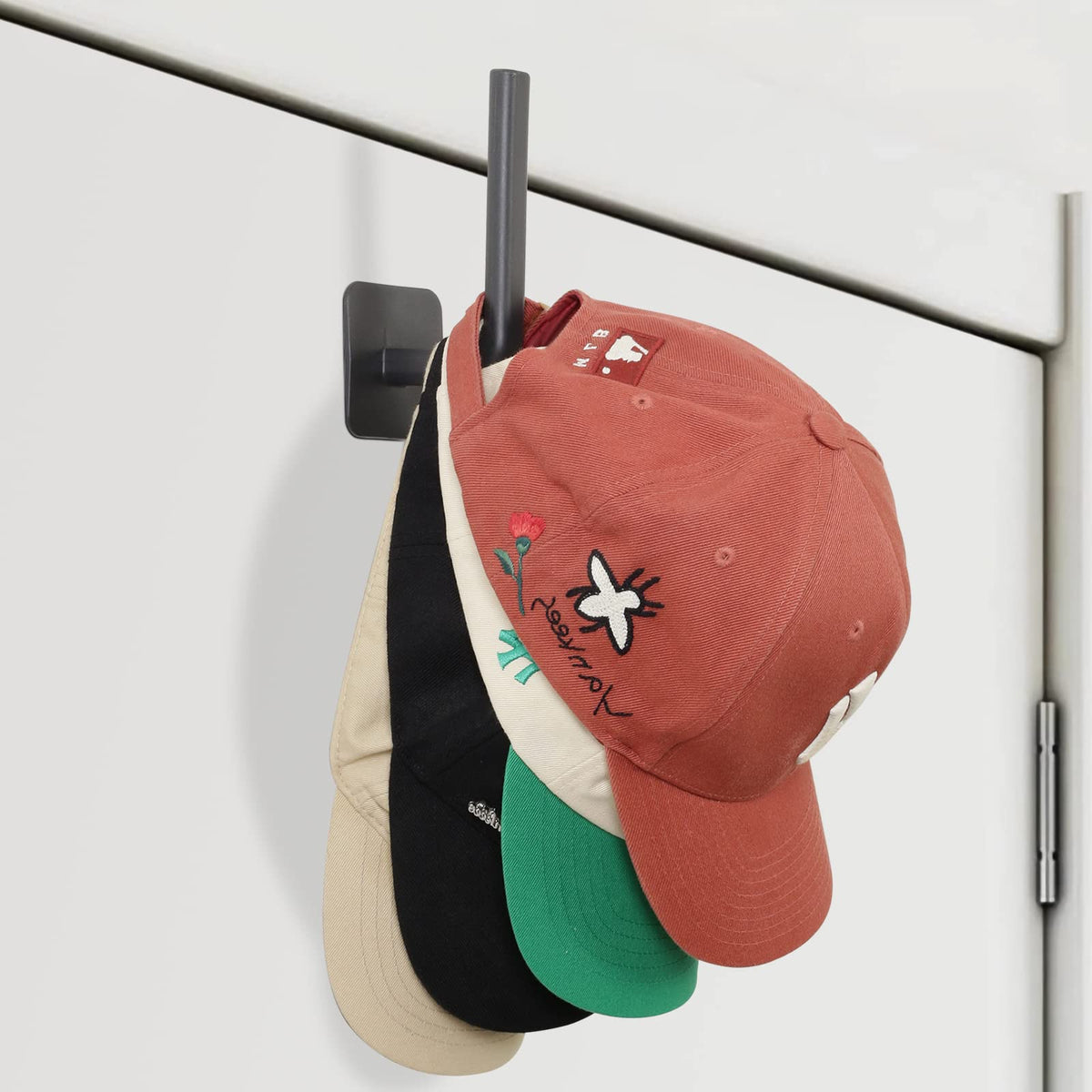 Adhesive cap hooks holding baseball caps on a wall